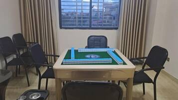 Una habitación con una mesa dispuesta para dos personas, una ventana con persianas y vistas a edificios.