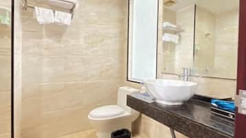 Un baño moderno con pared de mármol, un inodoro blanco, un espejo grande y un cesto de basura negro.
