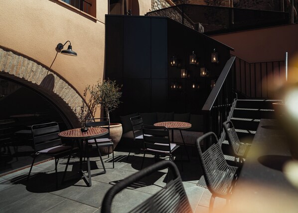 An outdoor seating area with tables and chairs, a potted plant, and a staircase. - ORA Hotel Priorat, a Member of Design Hotels (Torroja del Priorat)
