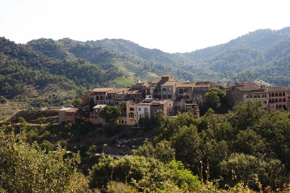 Un pueblo en una ladera con edificios tradicionales, campos en terrazas y abundante vegetación.