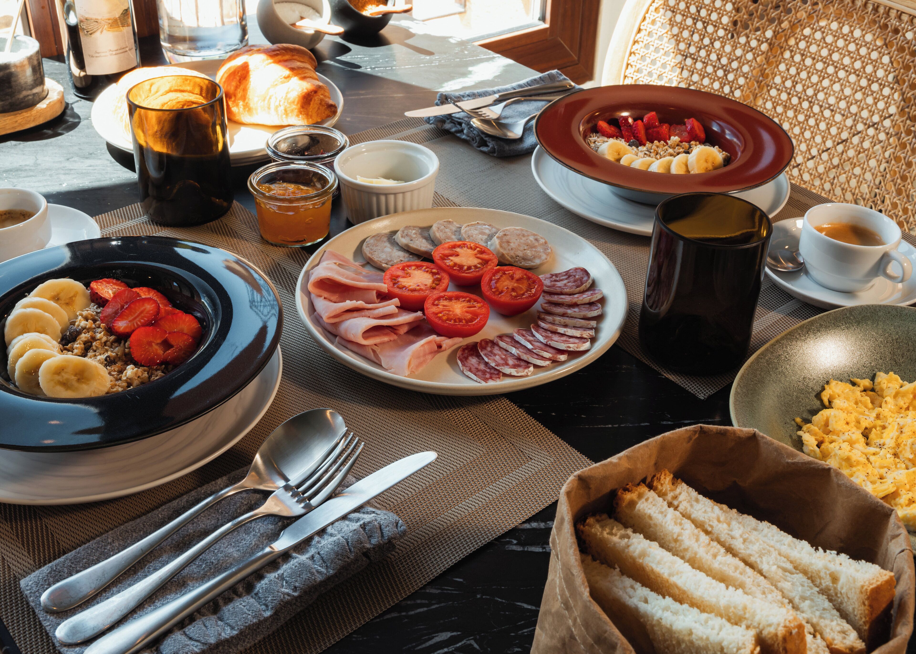 A breakfast setting with plates of food, a coffee cup, and breakfast items on a table.