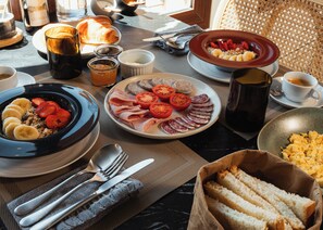 Una escena de desayuno con platos de comida, una taza de café y productos para el desayuno sobre una mesa.
