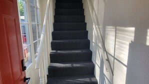 A staircase with a red door at the bottom, leading to an upper floor. - The Lakeside Micro Apartment (Muskegon)