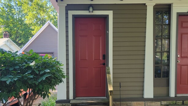A house with a red door, stone steps, and a small porch area. - The Lakeside Micro Apartment (Muskegon)