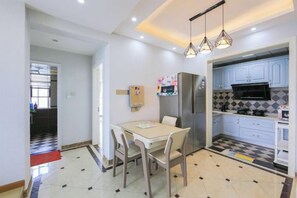 A modern kitchen with a dining area, featuring a refrigerator, microwave, and a tiled backsplash. - Huaxi Guesthouse (Zhangjiajie)