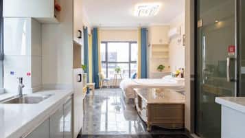 A modern hotel room with a kitchen area, a dining table, and a bed.