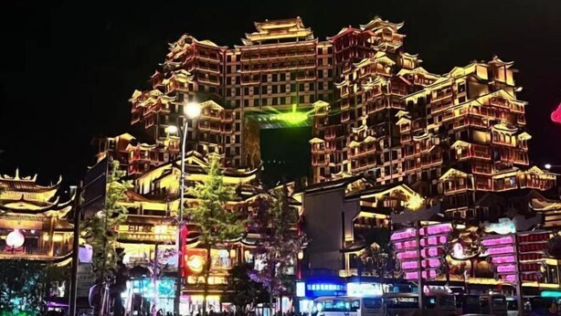 A multi-story building with traditional architectural elements, illuminated at night. - Huaxi Guesthouse (Zhangjiajie)