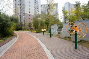 A paved pathway with a brick surface, flanked by greenery and a high-rise building in the background. - Huaxi Guesthouse (Zhangjiajie)