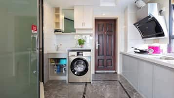 A compact kitchen with a built-in washing machine, a microwave, and a sink.