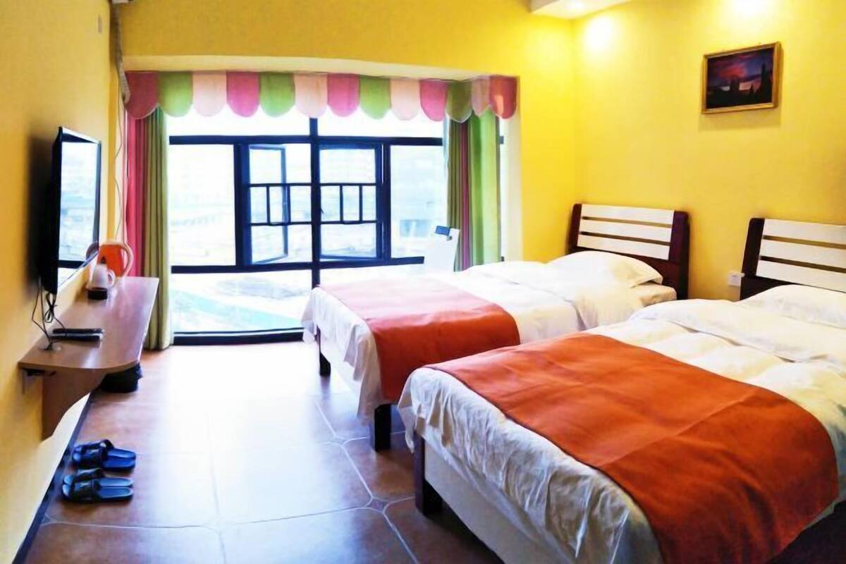 A hotel room with two beds, a desk with a computer, and a window with a view.