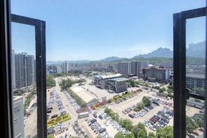 A view of a parking lot with multiple cars, buildings, and mountains in the background.