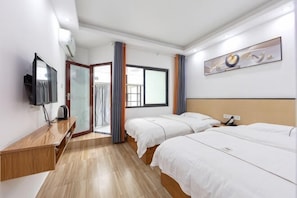 Habitación de hotel con dos camas, televisión, escritorio y ventana.