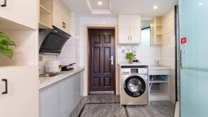 A compact kitchen with white cabinets, a washing machine, and a small countertop. - Huaxi Guesthouse (Zhangjiajie)