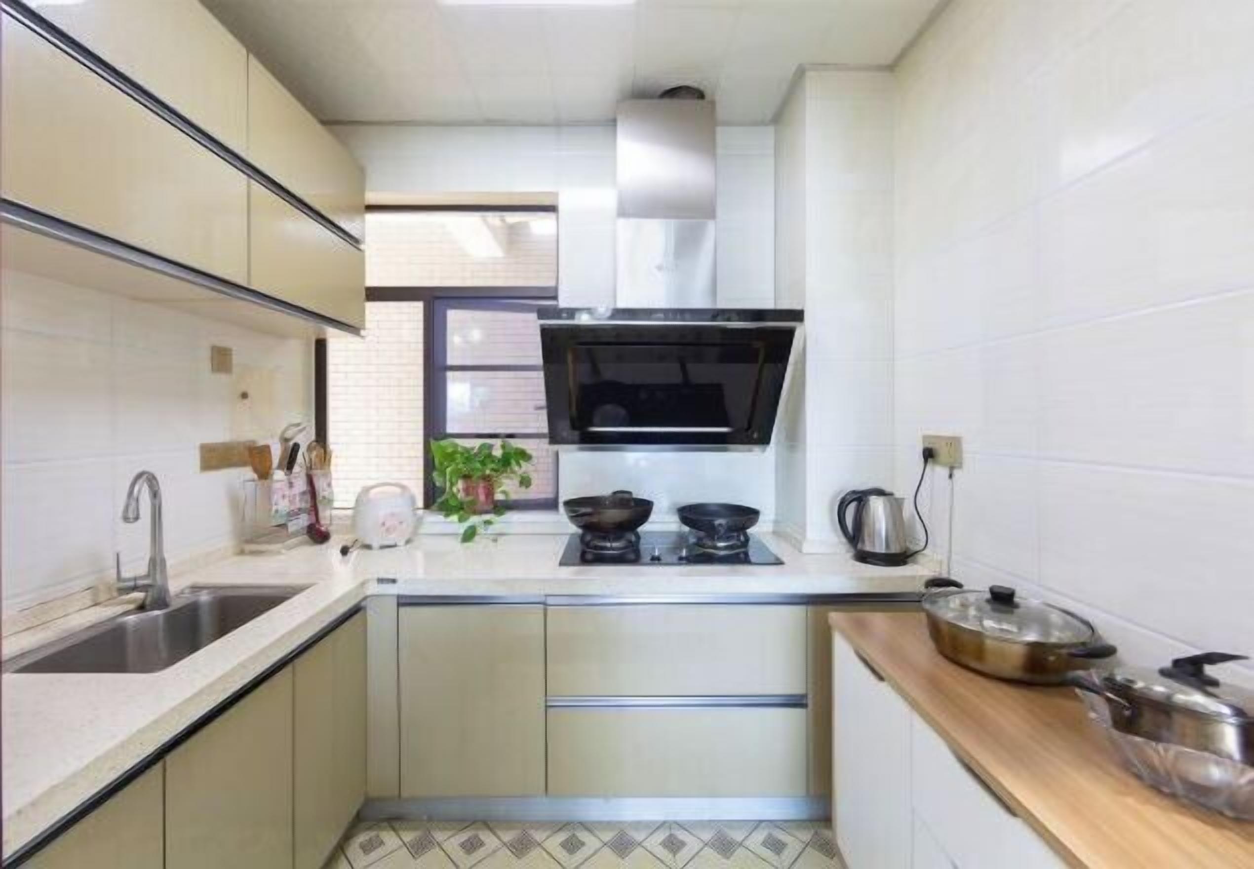 Une cuisine de taille réduite, équipée d’un évier, d’une cuisinière et de placards.