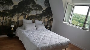 A bedroom with a large bed, a mural of trees on the wall, and a window with a view of greenery. - house with sea river view, with jacuzzi spa (Gouesnach)
