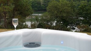 A hot tub with a clear view of a forested area and a body of water in the background. - house with sea river view, with jacuzzi spa (Gouesnach)