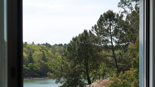A window view of a lake surrounded by trees and a grassy area. - house with sea river view, with jacuzzi spa (Gouesnach)