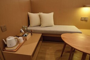 A compact room with a bed, a small table, and a seating area. - Lost&Found@Wutong House (Shenzhen)