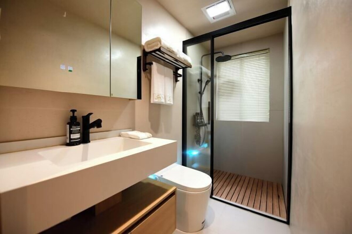 A modern bathroom with a white sink, black faucet, and a glass-enclosed shower.