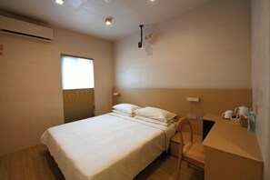 A clean, minimalist hotel room with a single bed, a chair, a small desk with a lamp, and a window providing natural light. - Lost&Found@Wutong House (Shenzhen)