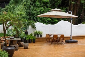 An outdoor seating area with a table, chairs, and a large umbrella. - Lost&Found@Wutong House (Shenzhen)
