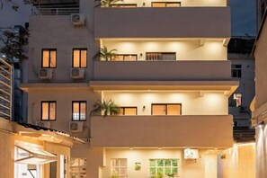 A multi-story building with balconies, air conditioning units, and a well-lit entrance. - Lost&Found@Wutong House (Shenzhen)