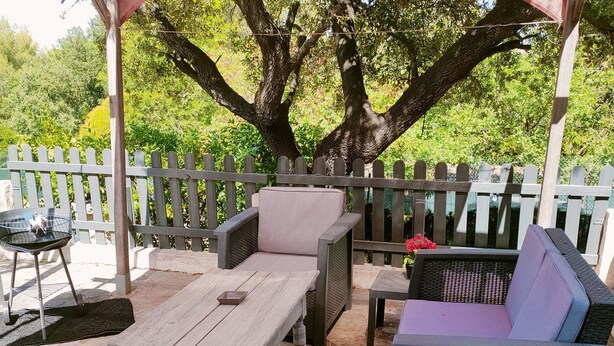 An outdoor patio with stone flooring, wicker furniture, and a wooden table. - self-contained 60m2 apartment in private grounds (Aubagne)