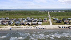 Une zone résidentielle côtière avec des maisons le long de la plage, un ciel dégagé et des vagues au premier plan.