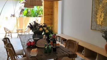 A dining area with a wooden table, wicker chairs, and a vase of flowers.