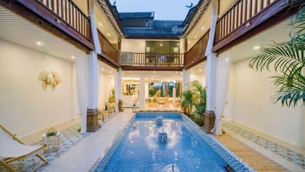 Ein Innenhof mit einem zentralen Pool, einem Holzdeck und einem überdachten Sitzbereich.