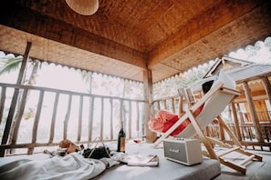 A wooden room with a bed, a table with a bottle, a glass, and a radio. - Lucky Clover Hotel (Jinghong)