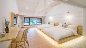 Ein modernes Schlafzimmer mit zwei Betten, einem Holztisch und einem großen Fenster.