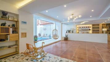 A spacious lobby with a reception desk, a seating area with a rocking chair, and a view of the outdoor patio.