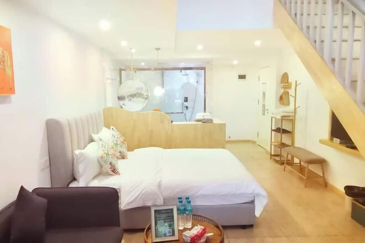 Een moderne hotelkamer met een bed, een bank, een eettafel en een trap.