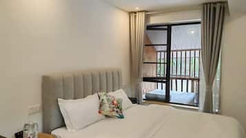 Habitación de hotel con cama, mesita de noche, ventana con cortinas y vista a un balcón.