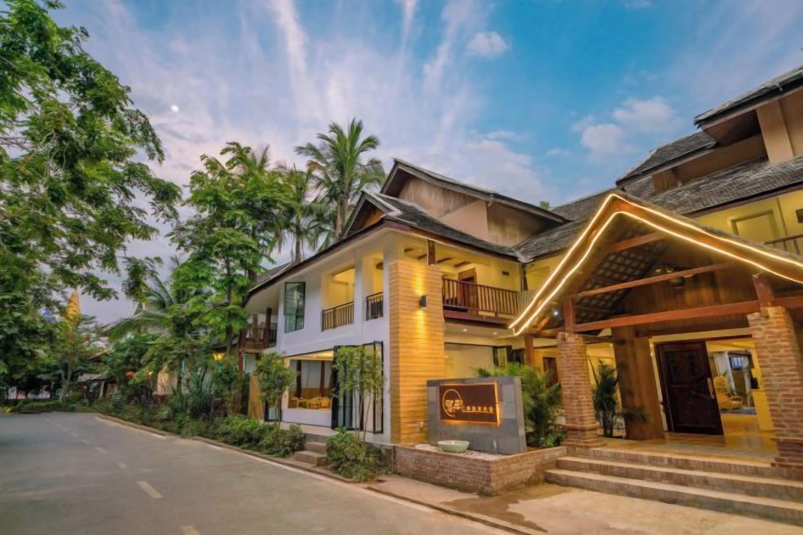 A hotel with a modern design, featuring a covered entrance, multiple balconies, and a signboard.