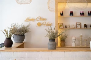 Un espace d’accueil avec un mur en briques blanches, un comptoir de réception en bois et une enseigne fixée au mur sur laquelle on peut lire : « Hôtel Ludwig Clara ».
