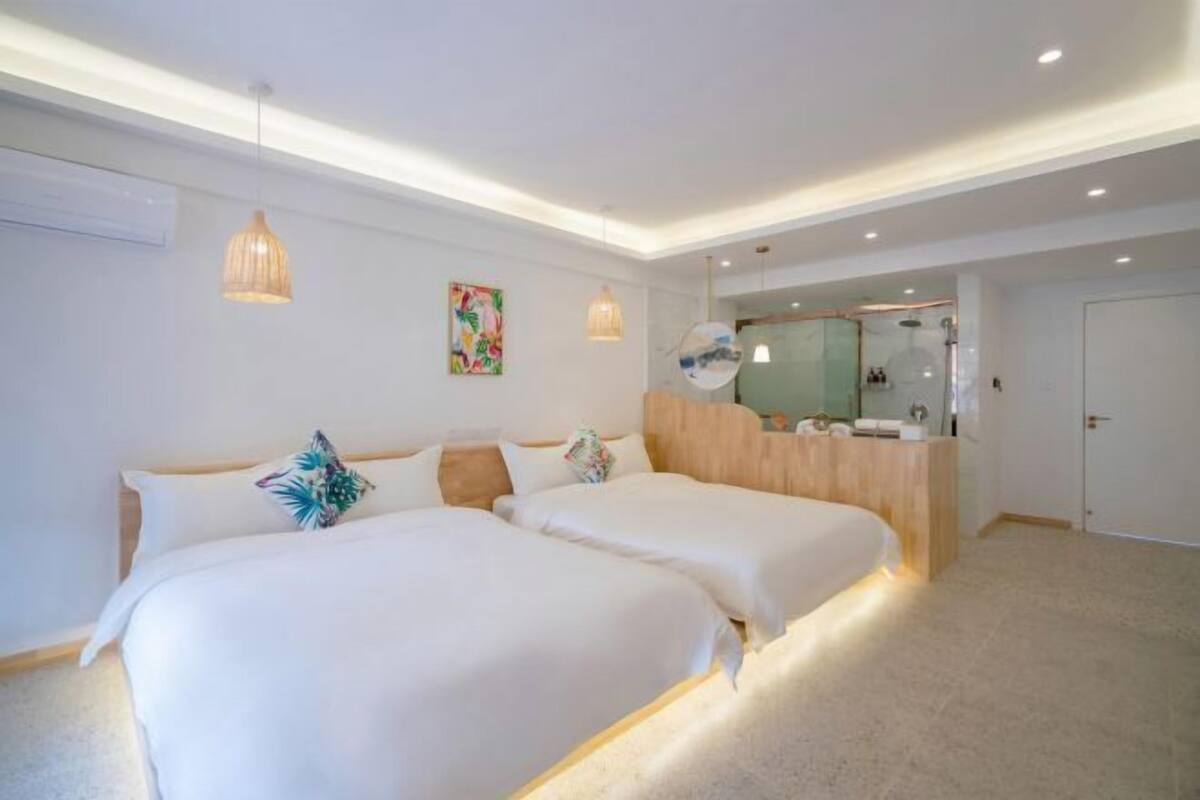 Een hotelkamer met twee bedden, een houten bureau, een spiegel en een douche.