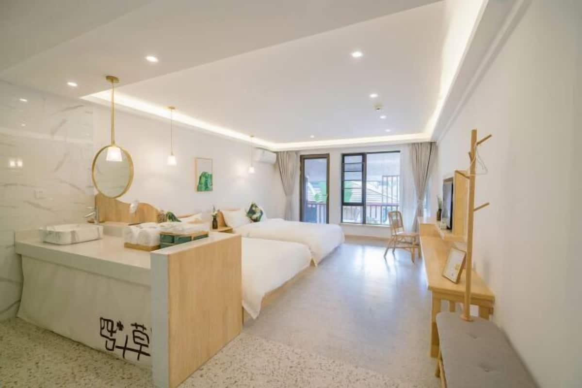 Een moderne hotelkamer met een centraal geplaatst bed, een klein bureau, een kaptafel met spiegel en een groot raam met uitzicht op het buitenland.