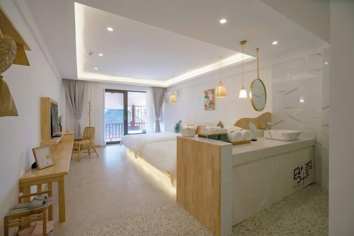 Een moderne hotelkamer met een bed, een bureau, een badkamer met een spiegel en een balkon.