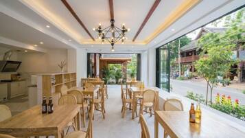 A dining area with wooden tables and chairs, a chandelier, and a view of the street outside.