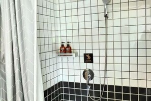 Ein Badezimmer mit Wänden aus weißen und schwarzen Fliesen, einer Duschkabine und einem Ablagebereich für Toilettenartikel.