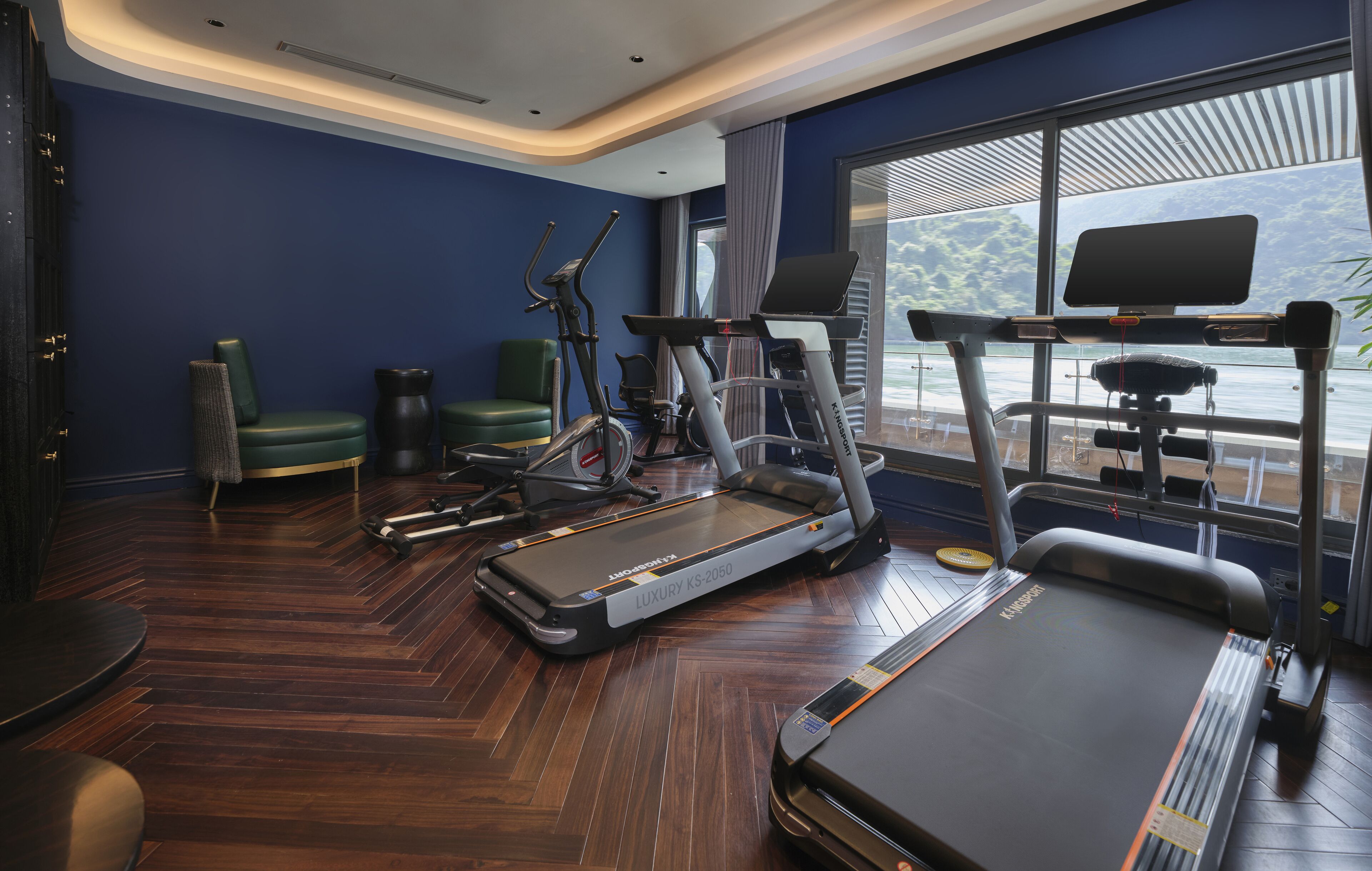 A modern hotel room with a treadmill, stationary bike, and exercise equipment.