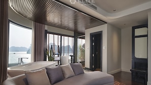 A modern living room with a curved sofa, a dining table, and a view of the sea. - Elite of the Seas (Tuan Chau)