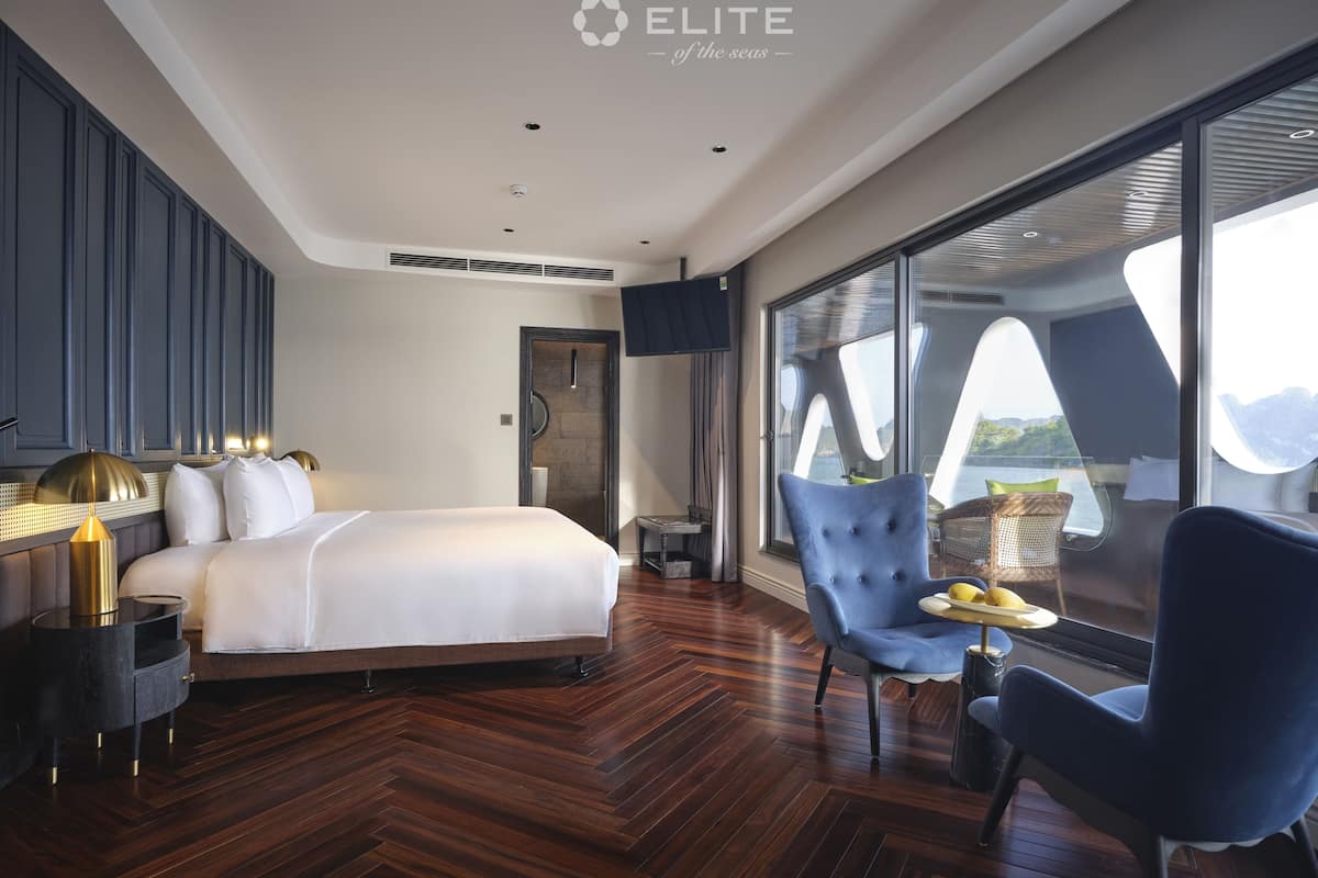 A modern hotel room with a large bed, a seating area with a view, and a large window.