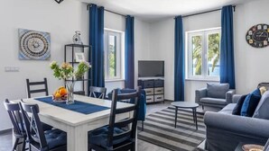 Una sala de estar moderna con comedor, un sofá, un televisor y un reloj en la pared.
