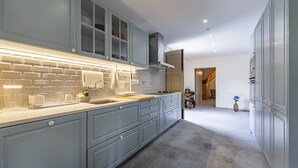 Uma cozinha moderna com armários azul-claros, bancada branca e painel de parede em tijolos.
