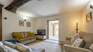 Uma sala de estar com dois sofás, uma televisão e um candelabro.