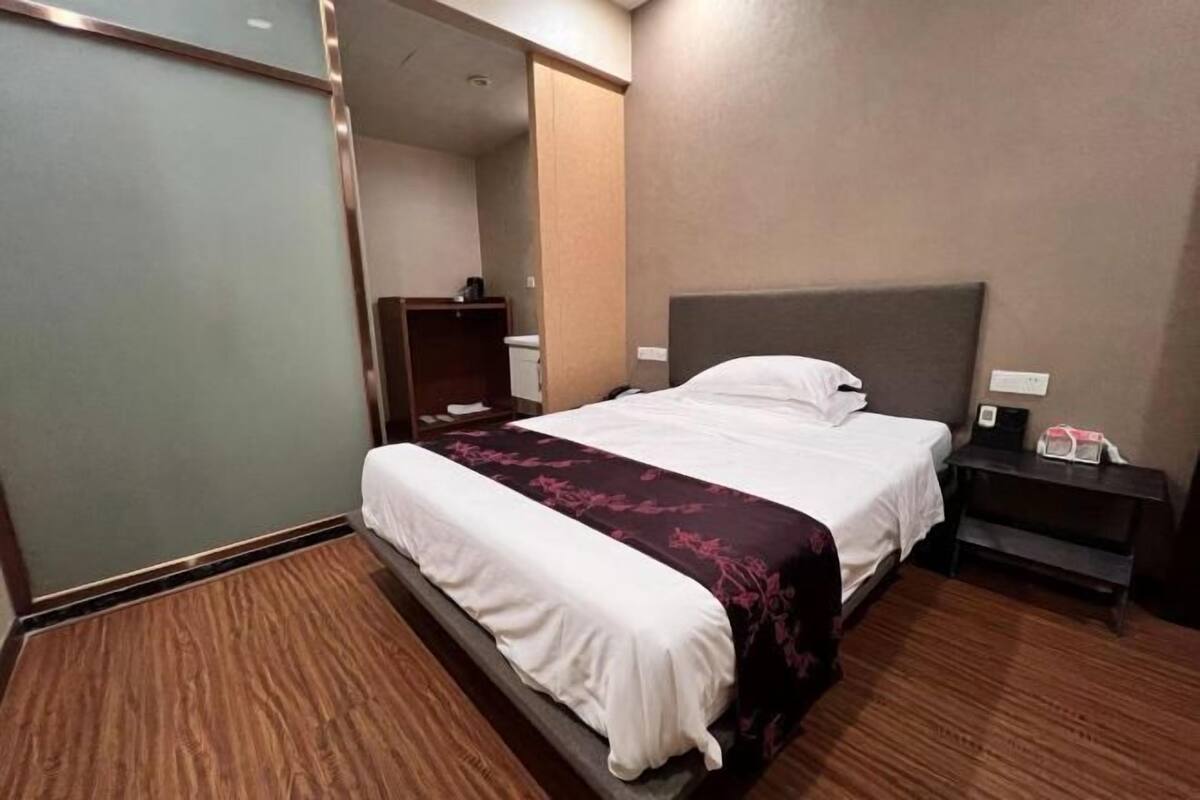 A hotel room with a bed, bedside table, and a wardrobe.