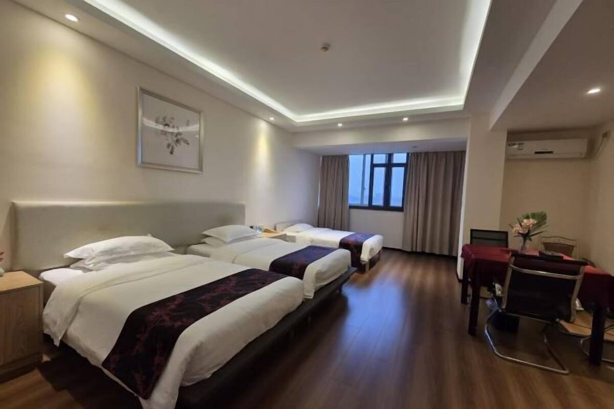 A hotel room with two beds, a desk, and a chair.
